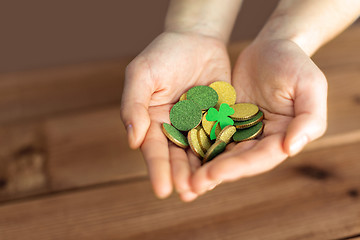 Image showing hands with golden coins and shamrock leaf