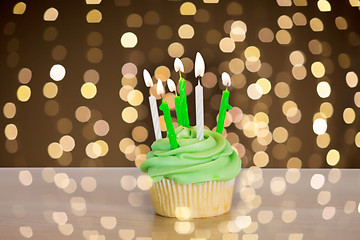 Image showing green cupcake with six burning candles on table