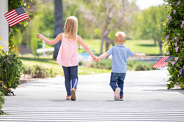 Image showing Young Sister and Brother Holding Hands and Waving American Flags