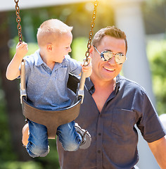 Image showing Happy Young Boy Having Fun On The Swings With His Father At The 