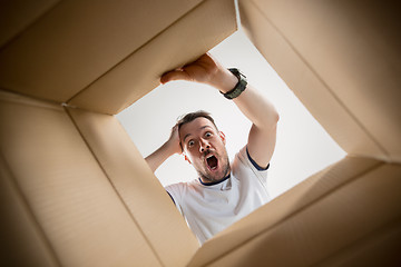 Image showing Man unpacking and opening carton box and looking inside