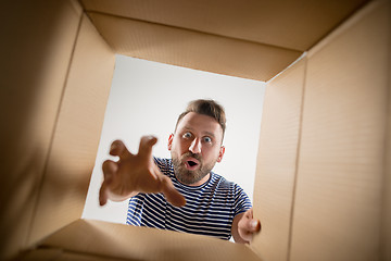 Image showing Man unpacking and opening carton box and looking inside