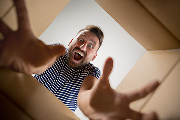 Image showing Man unpacking and opening carton box and looking inside