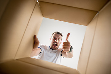 Image showing Man unpacking and opening carton box and looking inside