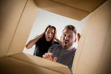 Image showing The couple unpacking and opening carton box and looking inside