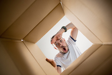 Image showing Man unpacking and opening carton box and looking inside