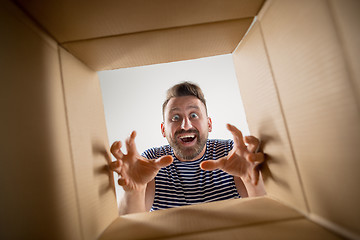 Image showing Man unpacking and opening carton box and looking inside