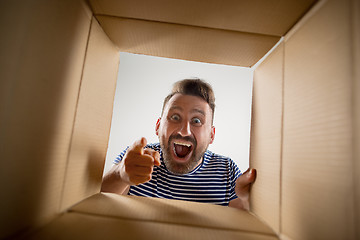 Image showing Man unpacking and opening carton box and looking inside