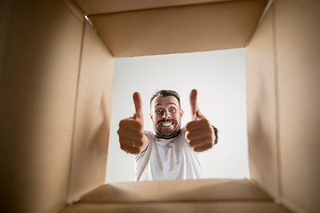 Image showing Man unpacking and opening carton box and looking inside