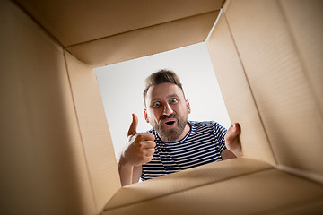 Image showing Man unpacking and opening carton box and looking inside