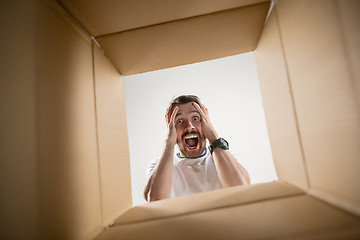 Image showing Man unpacking and opening carton box and looking inside