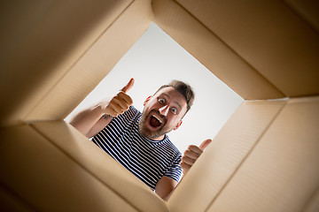 Image showing Man unpacking and opening carton box and looking inside