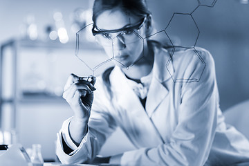 Image showing Portrait of a confident female researcher in life science laboratory writing structural chemical formula on a glass board.