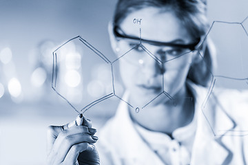 Image showing Portrait of a confident female researcher in life science laboratory writing structural chemical formula on a glass board.