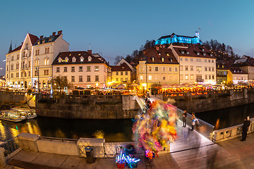 Image showing View of lively river Ljubljanica bank in old city center decorated with Christmas lights at dusk. Old medieval Ljubljana cstle on the hill obove the city. Ljubljana, Slovenia, Europe