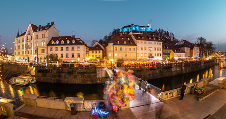 Image showing View of lively river Ljubljanica bank in old city center decorated with Christmas lights at dusk. Old medieval Ljubljana cstle on the hill obove the city. Ljubljana, Slovenia, Europe