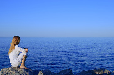 Image showing Girl sitting on the rock by the peaceful sea