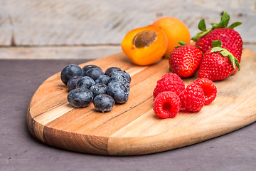 Image showing Wooden board with fresh organic fruit and berries