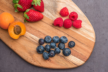 Image showing Wooden board with fresh organic fruit and berries