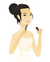 Image showing Young asian bride paints lips with red lipstick.