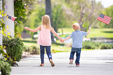 Image showing Young Sister and Brother Holding Hands and Waving American Flags