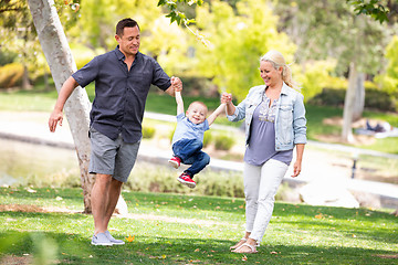 Image showing Young Mother and Father Swingging Their Son At The Park