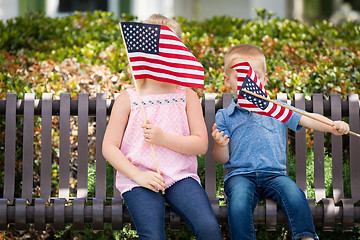 Image showing Young Sister and Brother Waving American Flags On The Bench At T