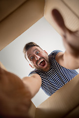 Image showing Man unpacking and opening carton box and looking inside