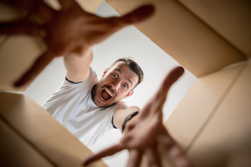 Image showing Man unpacking and opening carton box and looking inside