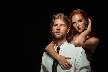 Image showing Real passion. Beautiful young loving couple bonding to each other while both standing against black studio walls