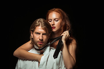 Image showing Real passion. Beautiful young loving couple bonding to each other while both standing against black studio walls