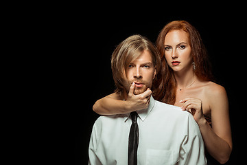 Image showing Real passion. Beautiful young loving couple bonding to each other while both standing against black studio walls