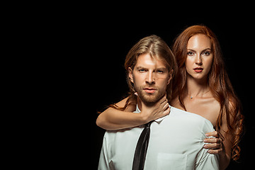 Image showing Real passion. Beautiful young loving couple bonding to each other while both standing against black studio walls