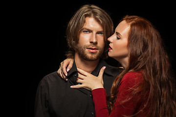 Image showing Real passion. Beautiful young loving couple bonding to each other while both standing against black studio walls