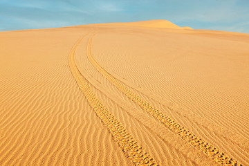 Image showing All-terrain vehicle ATV tracks in white sand dunes on sunrise,