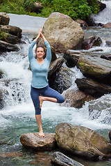 Image showing Woman in yoga asana Vrikshasana tree pose at waterfall outdoors