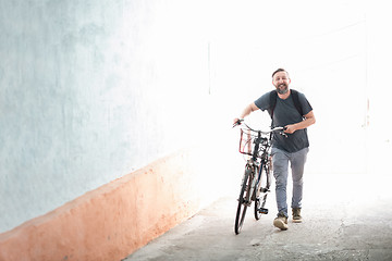 Image showing hipster man with a backpack pushing a retro bicycle