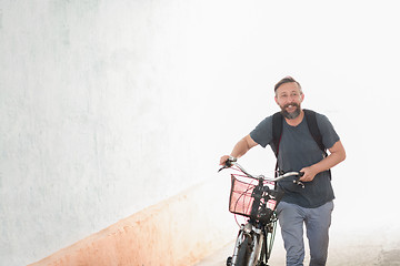 Image showing hipster man with a backpack pushing a retro bicycle