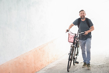 Image showing hipster man with a backpack pushing a retro bicycle