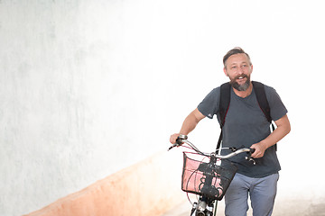 Image showing hipster man with a backpack pushing a retro bicycle