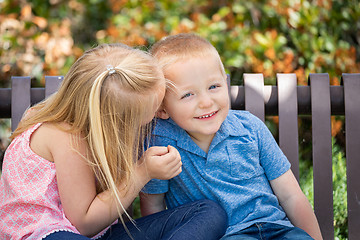 Image showing Young Sister and Brother Whispering Secrets On The Bench At The 