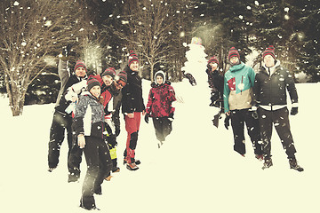 Image showing group portait of young people posing with snowman