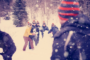 Image showing group of young people making a snowman