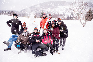 Image showing group portait of young people posing with snowman