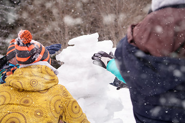 Image showing group of young people making a snowman