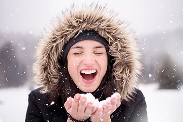 Image showing young woman blowing snow on snowy day