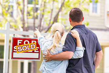 Image showing Caucasian Couple Facing and Pointing to Front of Sold Real Estat