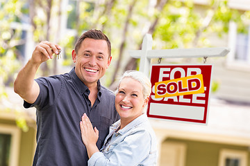 Image showing Caucasian Couple in Front of Sold Real Estate Sign and House wit