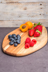 Image showing Wooden board with fresh organic fruit and berries