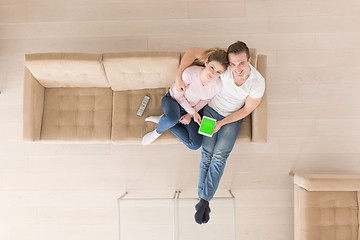 Image showing young couple in living room using tablet top view